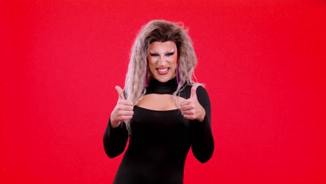 drag queen posing with thumbs up on red background