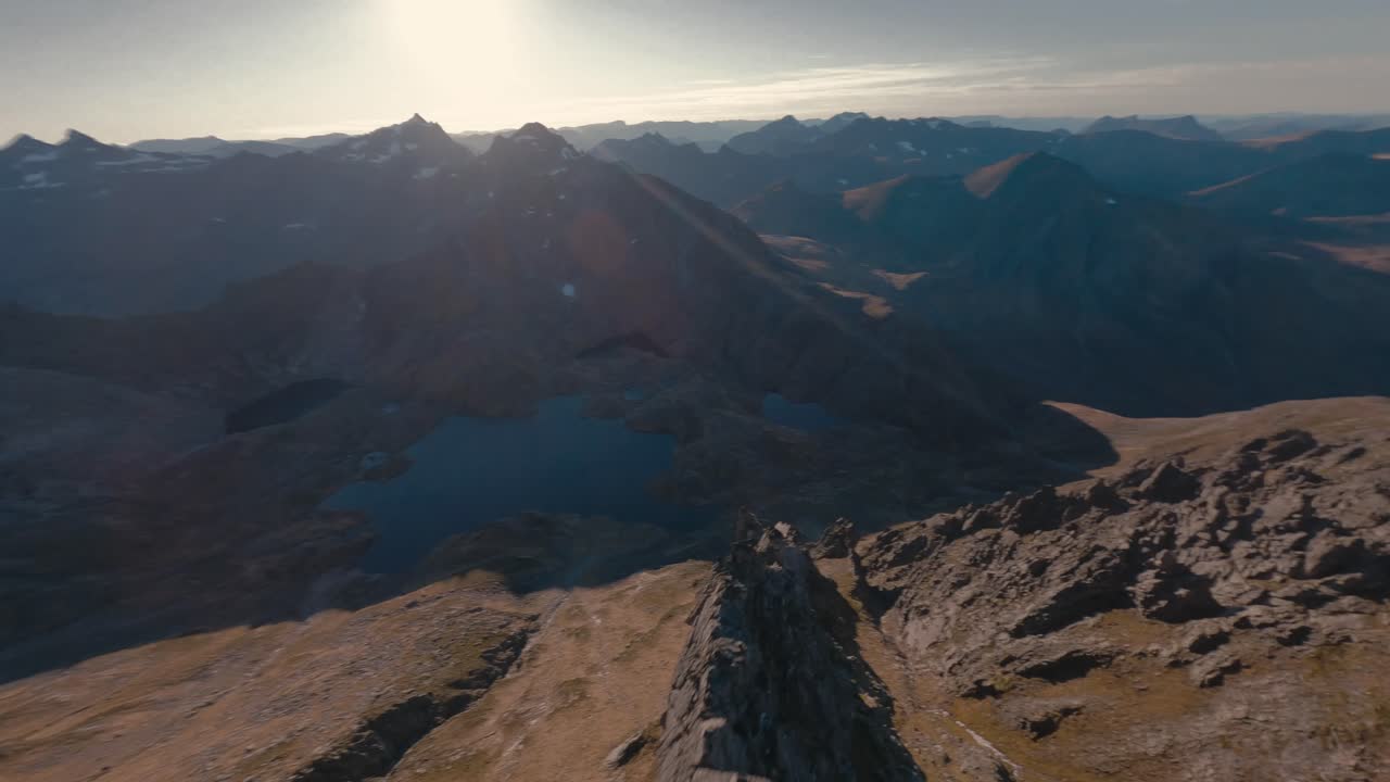 Volo FPV in discesa su un pendio roccioso in una valle con un lago a Molladalen, Norvegia, alla luce del sole