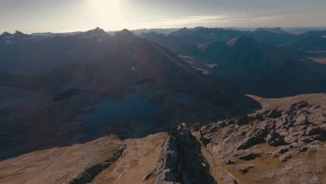 Fpv-flight-downhill-rocky-slope-into-valley-with-Lake-in-Molladalen,-Norway-at-sunlight