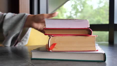 a stack of books on a table by a window