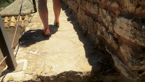 close-up of a person walking along ancient stone steps, surrounded by rustic walls in ronda, spain