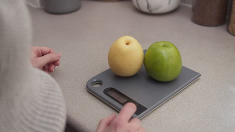 Hände-Legen-Einige-Früchte-Auf-Die-Küchenwaage,-Um-Sie-Aus-Nächster-Nähe-Zu-Wiegen