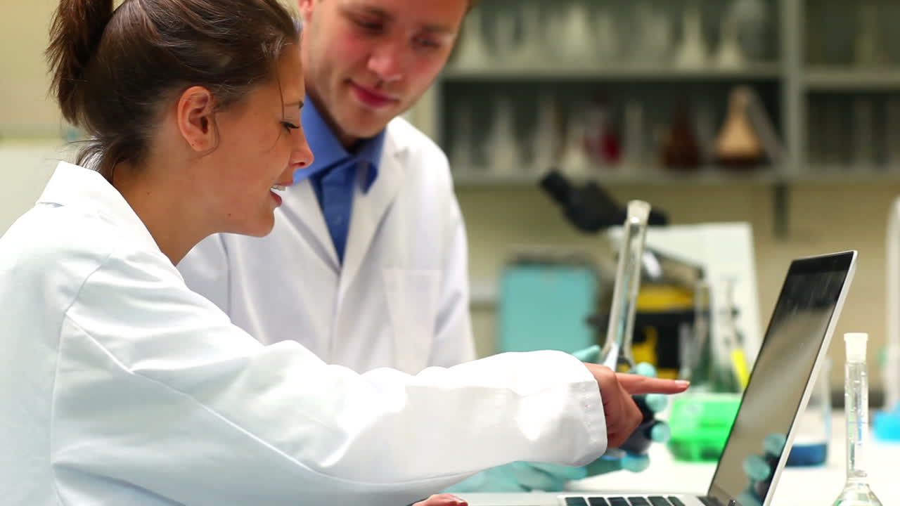 Studenti di scienze che esaminano una sostanza chimica e usano un portatile.