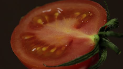 Drehen-Der-Hälften-Frischer,-Reifer,-Geschnittener-Tomaten-Auf-Dunklem-Hintergrund