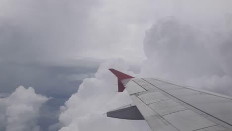 view of sky through plane window while flying over fluffy cloud sky scape in daytime with wing view ,aerial view above the clouds and sky inspiration concept,natural background cloudscape