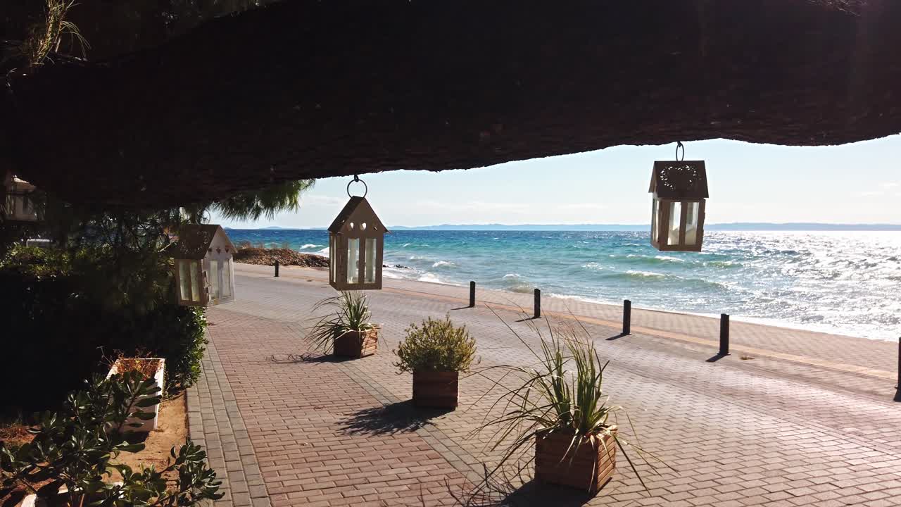 Swaying in the wind cases for candles suspended by a tree branch, Aegean sea on the background in Nikiti, Greece. Slow motion