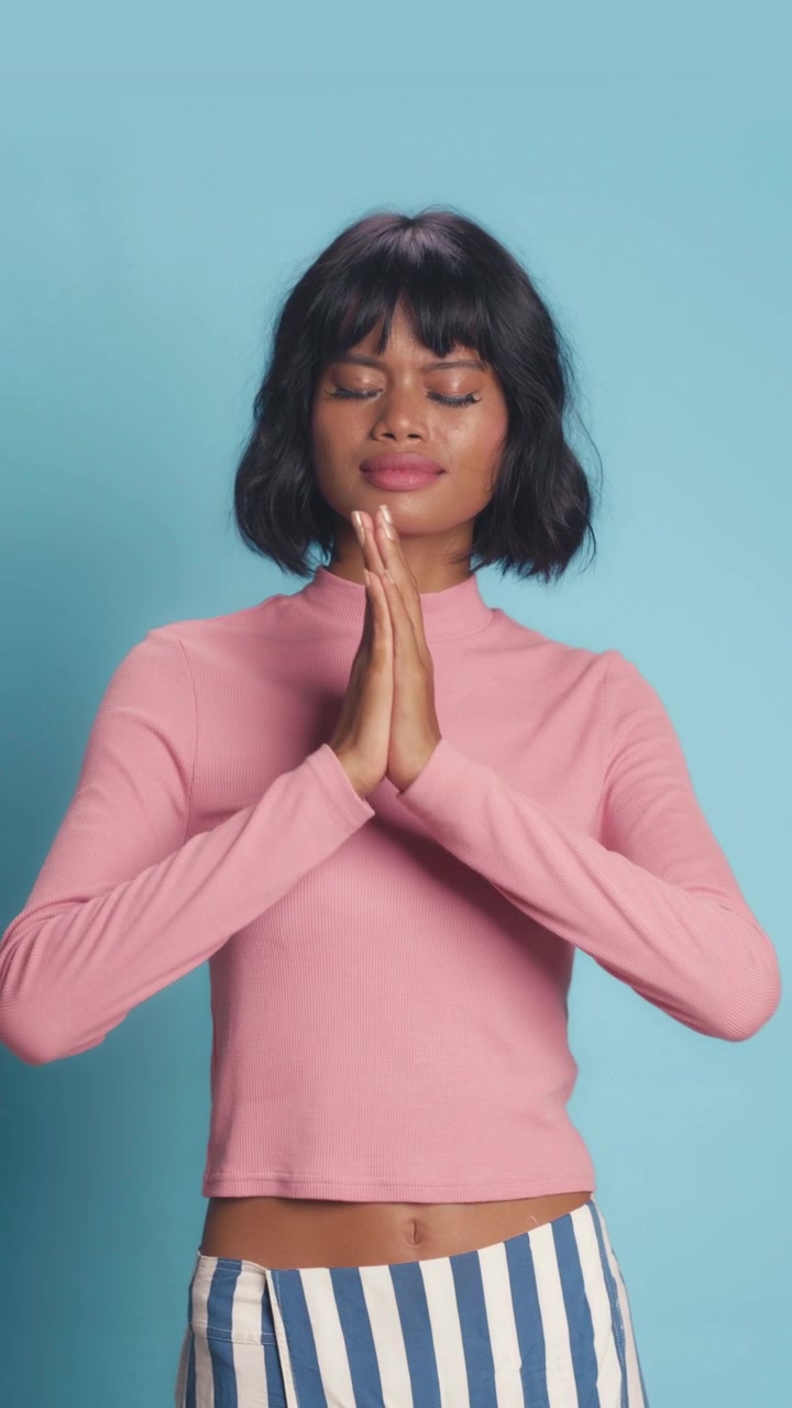 Southeast asian woman holding hands together in quiet prayer or meditation