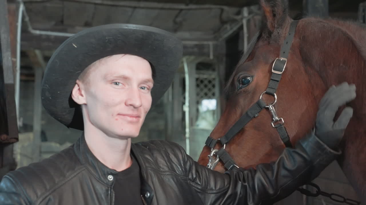 Uomo bianco che accarezza un cavallo in una stalla, carezze delicate e sorriso caloroso, connessione tra addestratore e cavallo dopo una lezione in tandem, capezza e briglia visibili, luce rustica soffusa e atmosfera calma che mostra fiducia.