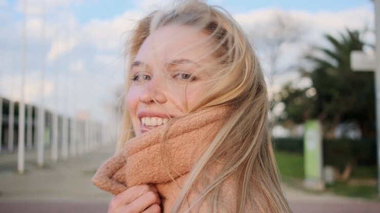 Giovane donna che si copre il viso con il cappotto