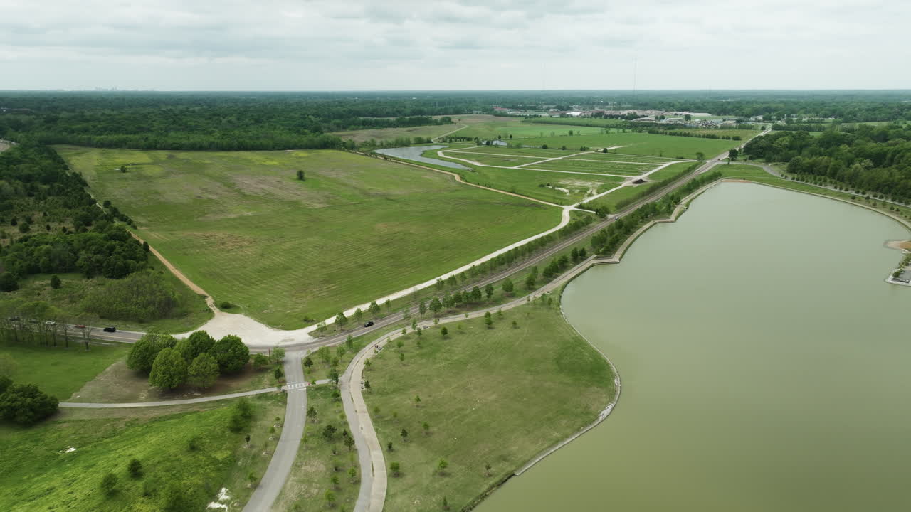 Parco Shelby Farms a Memphis con vegetazione lussureggiante, uno specchio d'acqua e sentieri pedonali, in una giornata nuvolosa, vista aerea