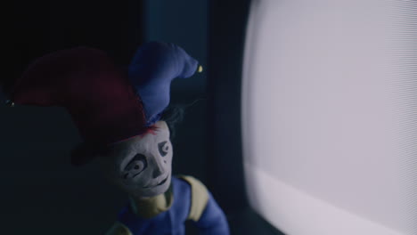 creepy jester puppet in front of an old tv
