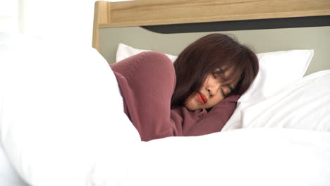 Asian-woman-sleeping-on-bed-in-morning