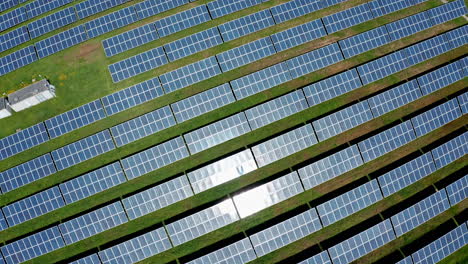 Rows-of-solar-panels-on-green-grass-seen-from-above-on-a-sunny-day