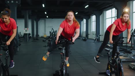 grupo de chicas atléticas realizando ejercicios de entrenamiento de conducción aeróbica en bicicleta estacionaria en el gimnasio