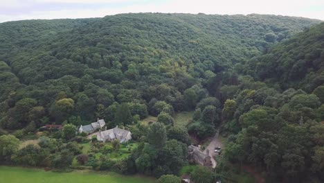 aerial tracking forward from the coastline over the fields and forests on the edge of exmoor, manor or country house in the foreground