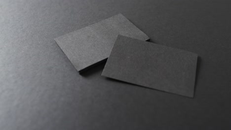 close up of stack of black business cards on black background, copy space, slow motion