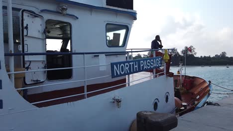 the government ferry in the andaman islands india docked waiting for its next round of passengers with the silhouette of a person who works on the boat seen at the stern and incredible india slogan