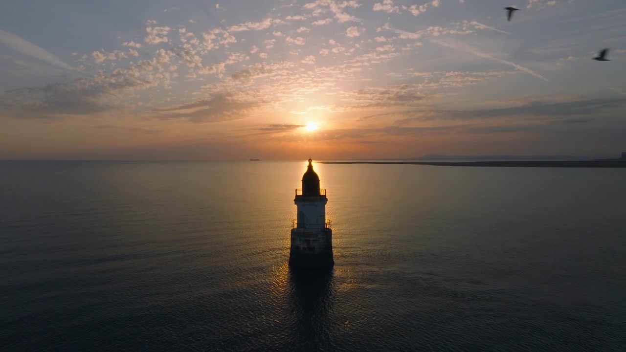 Faro abbandonato di Plover Scar. Baia di Morecambe, Lancashire, Regno Unito. Faro posizionato davanti al bagliore del tramonto. Lento avvicinamento con uccelli marini che passano