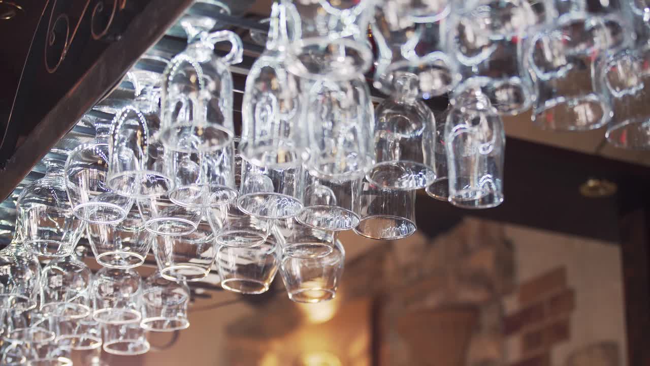 Empty crystal glasses hang at the glassware holder at bar counter. Beautiful new glasses from glass hanging in even rows.