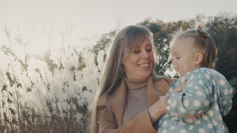 retrato de una madre joven feliz con su pequeña hija. juntos en un paseo por el parque de otoño