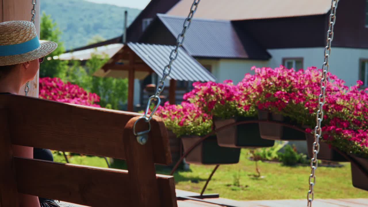 Woman in Straw Hat Enjoying a Sunny Day on a Garden Swing
