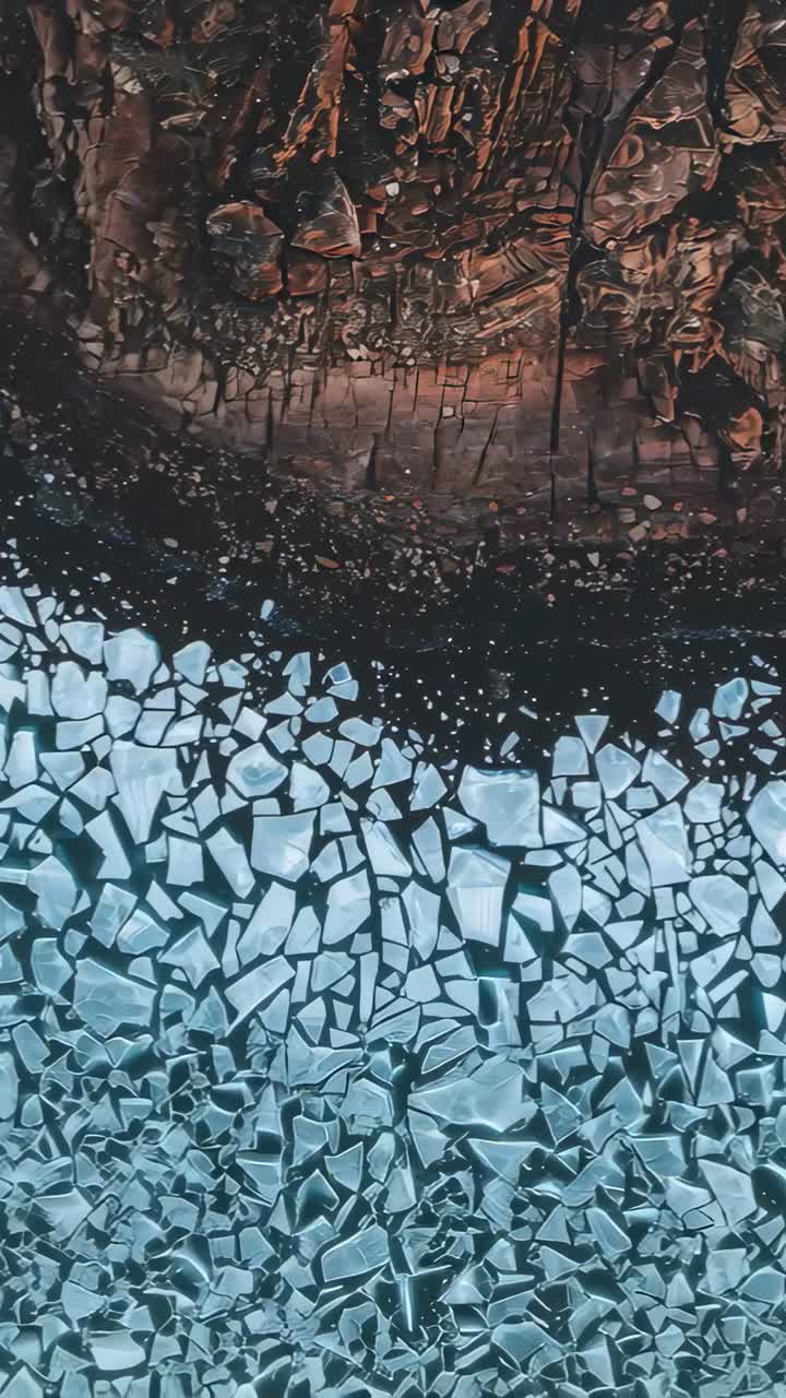 Vertical video: Descending drone showing ice floes shifting to show shore, dark channel forming