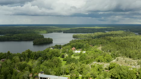 vista aérea lejos de la mansión fagervik, en el lago brunkstrasket, parcialmente soleado, día de verano, en inkoo, uusimaa, finlandia - reversa, inclinación hacia arriba, tiro con drones