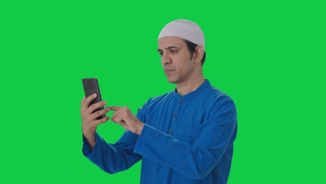 serious muslim man using phone green screen