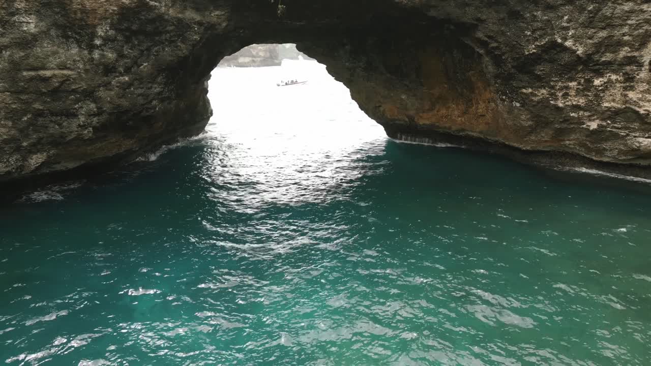 Aerial Push in view over green trees standing over the beautiful Nusa Penida Broken Beach in Bali Indonesia
