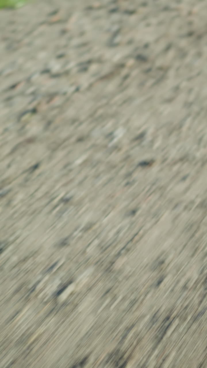 A blurred motion view of a gravel road surface as the ground rushes by