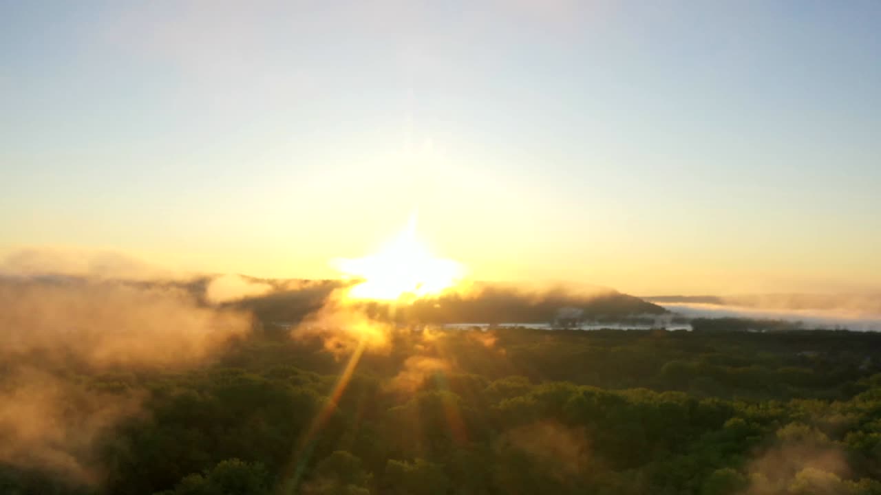 Time-lapse de amanecer dorado sobre bosque y montañas neblinosas