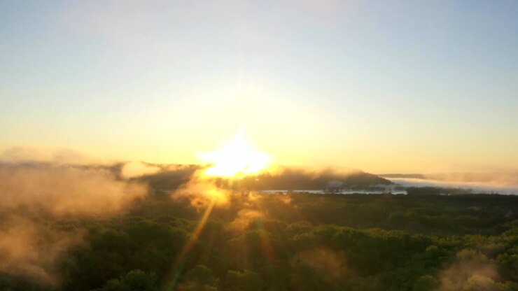 Time-lapse de amanecer dorado sobre bosque y montañas neblinosas