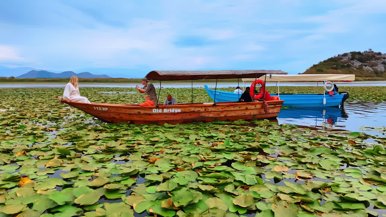 Ulcinj, Montenegro, 14 August 2025: Tour Boat on Wide Lake. A tour boat sails across a wide peaceful lake with mountain views