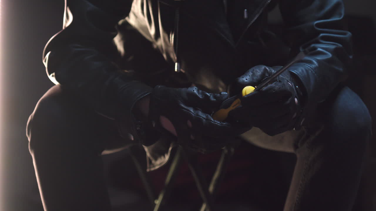 un criminal saca un destornillador de una bolsa negra y lo inspecciona