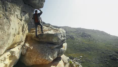 male hiker walking with backpack near a cave 4k