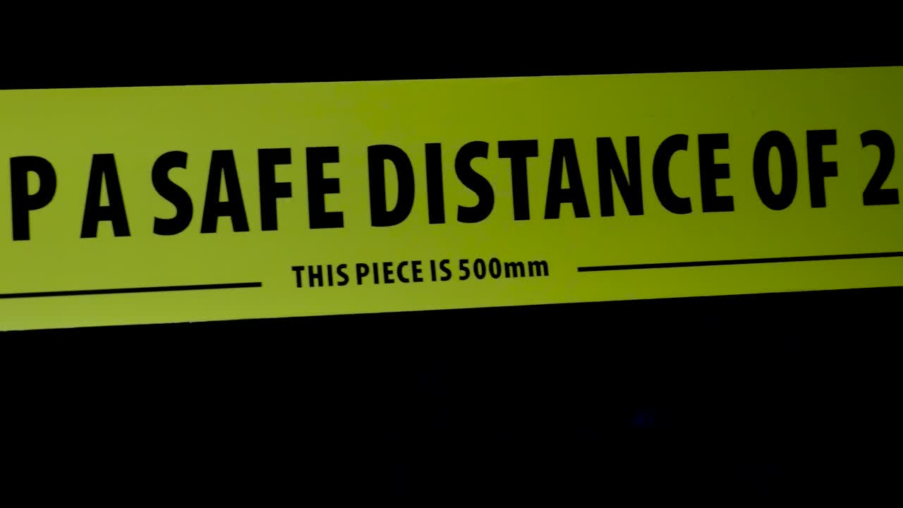 검정색 배경에 대한 노란색 사회적 거리 밴드의 샷