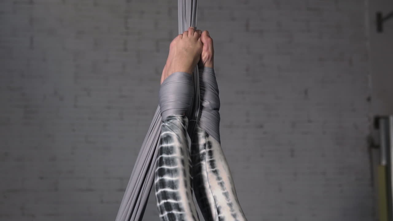 곡예 실크 운동을 하고 있는 그녀의 발에 매달려 있는 여자