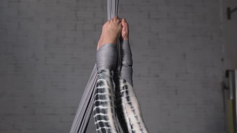 woman hanging from her feet doing acrobatic silks exericse