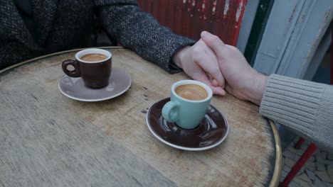 Couple-holding-hands-and-moving-apart-over-a-cup-of-coffee