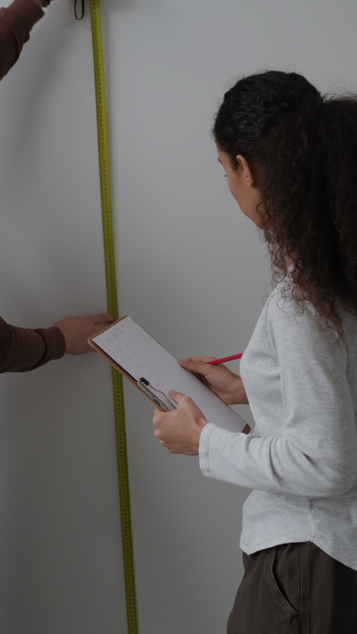 Woman taking measurements of a wall for home renovation