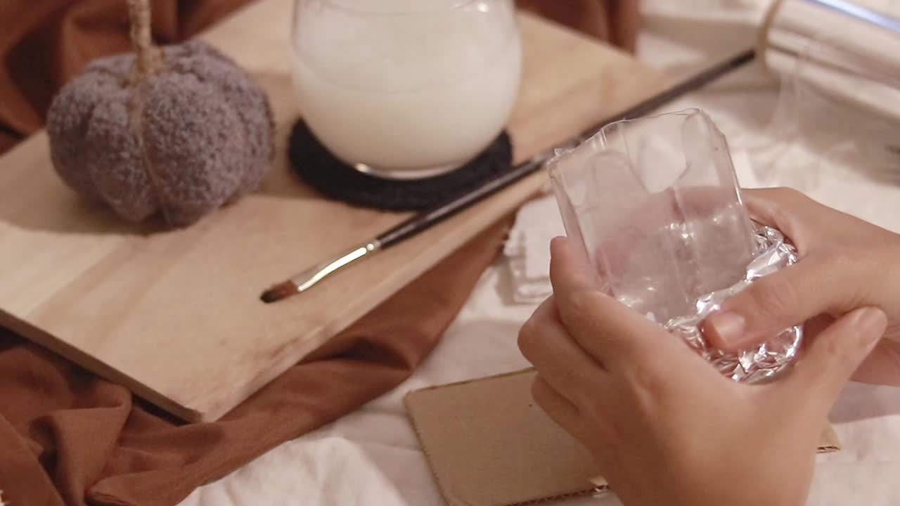 Hands crumpling and shaping tin foil around a plastic bottle to create a rabbit shape mold, DIY Easter theme recycle craft project