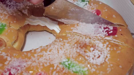 closeup, cutting slice of roscon de reyes spanish christmas pastry with knife