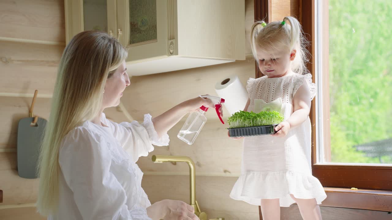 Mother and Daughter Watering Microgreens in the Kitchen