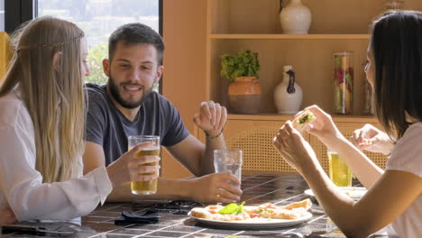 group of friends eating pizza and drinking beer at restaurant