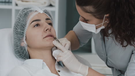 a woman receiving a cosmetic injection on her lips from a beautician