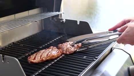 a person grills a beef steak on a barbecue, using tongs to flip it. bright lighting enhances the cooking process