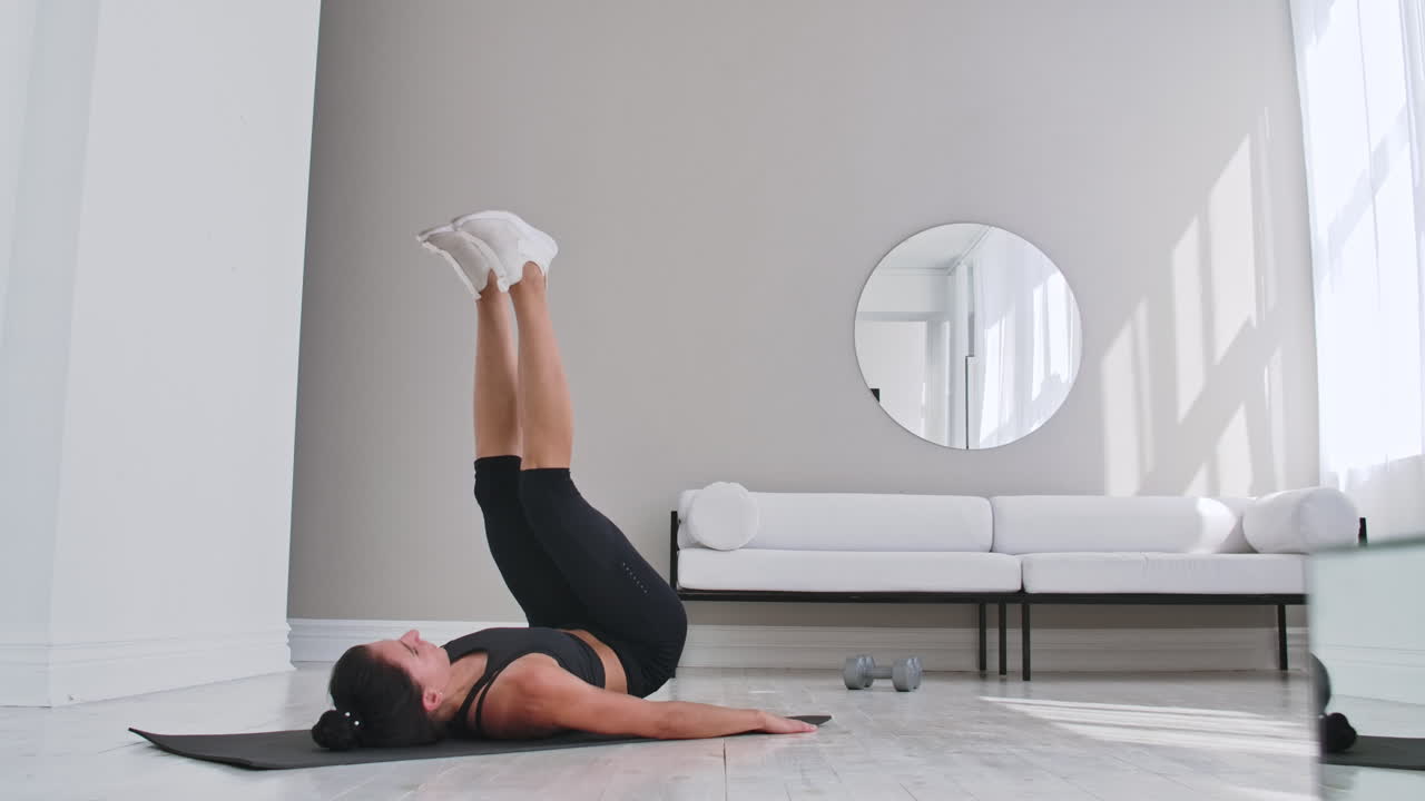 Strength training body weight workout woman athlete doing Flutter Kicks. European female adult doing floor exercises with Leg Raises to exercise abs muscles at home in his apartment