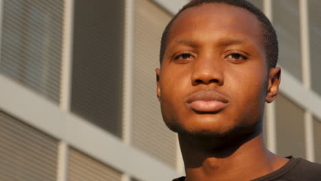 portrait of young black man looking at camera outdoors. handsome african american male athlete in sportswear resting on a sunny afternoon. close-up.