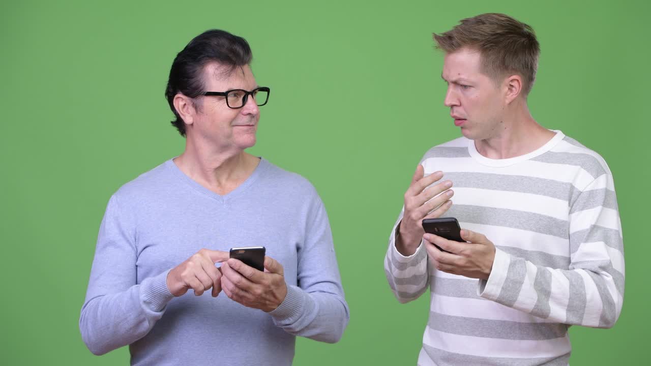 Senior handsome man and young handsome man using phone together