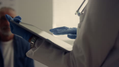 las manos del médico sosteniendo la computadora comprobando los datos del paciente en el hospital de cerca.